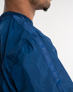 Man in a navy sauna suit tracksuit with a white boxraw logo on the chest as well as adjustable wrist straps and made from polyester.